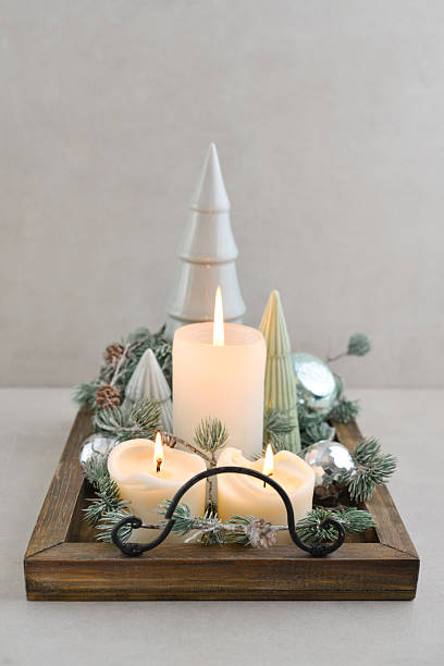 Decorative ceramic fir trees with blue christmas balls   and candles on wooden tray on dark wooden background