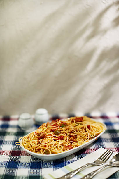 Spicy Spaghetti stir fried with bacon, dried chili and basil on white plate. Thai fusion Italian food style. Isolated on white background