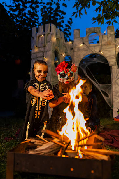 istock Children in Halloween costumes warming hands over a fire at night. 2234486087