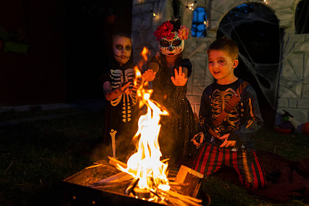 istock Children in Halloween costumes warming hands over a fire at night. 2234486202