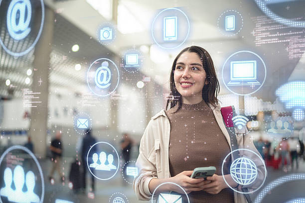 istock Young woman using mobile phone and looking data on augmented reality at airport 2234486661