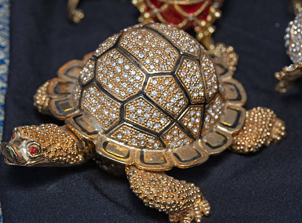 Close-up of golden turtle ornament decorated with sparkling crystals. Luxury decorative figure with detailed texture and shiny surface.