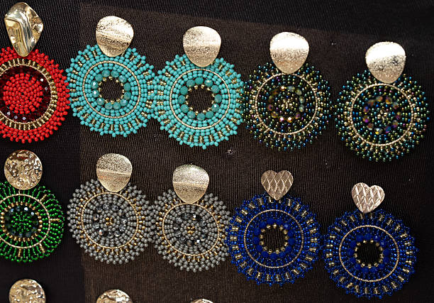 istock Handmade circular beaded earrings with gold details on dark background. 2234488765
