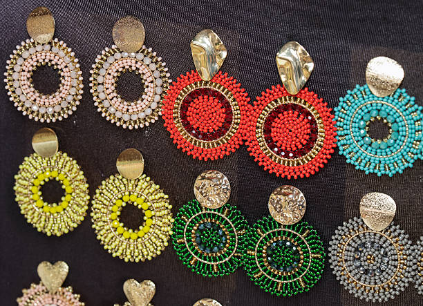 istock Handmade circular beaded earrings with gold details on dark background. 2234488770