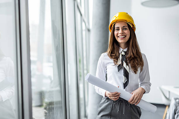 istock Female architect smiling and holding blueprints in office 2234490014