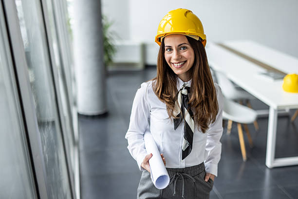 istock Female architect smiling and holding blueprints in office 2234490018