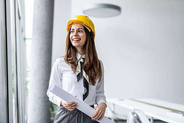 istock Female architect smiling and holding blueprints in modern office 2234490039