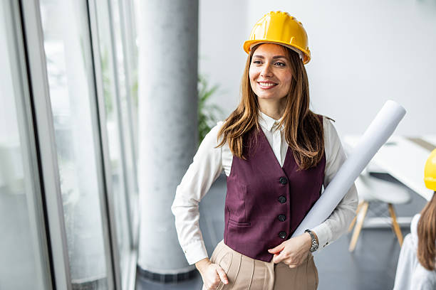 istock Female architect smiling and holding blueprints in office 2234490113