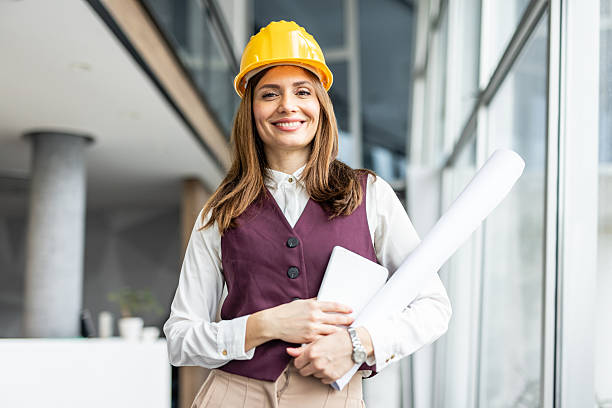 istock Female architect smiling at camera holding plans and tablet 2234490129