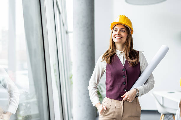 istock Confident female architect smiling and holding blueprints in modern office 2234490130