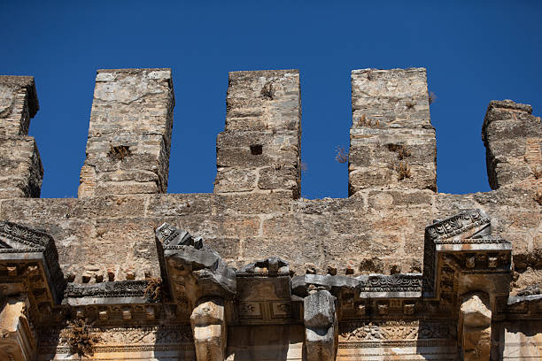 Ancient stone walls rise against a bright sky.