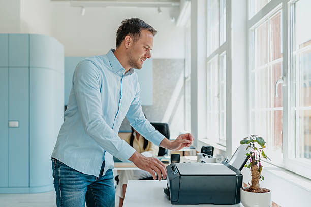 istock Businessman engaged in productive work at modern office desk with printer and plants 2234491289