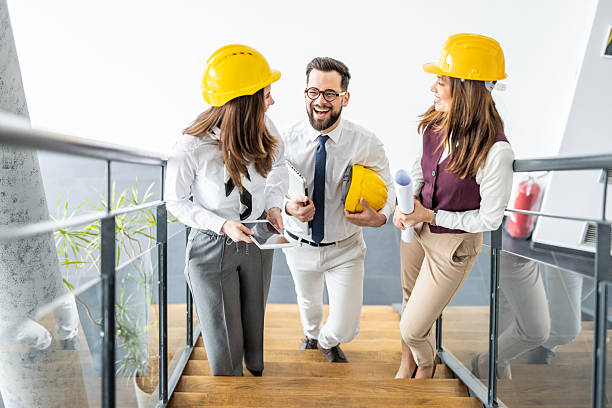 istock Architects walking downstairs holding blueprints and digital tablet 2234491321