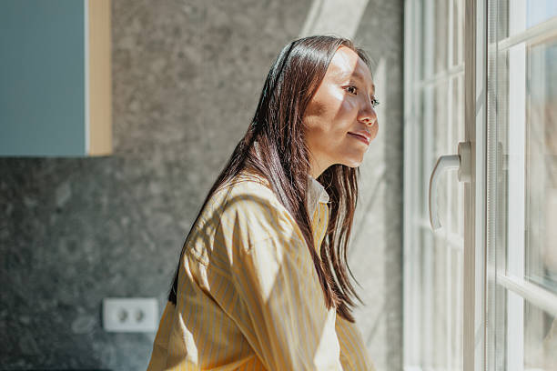 istock Professional Asian woman looking thoughtfully out the window in a modern office environment reflecting on her career aspirations 2234492969