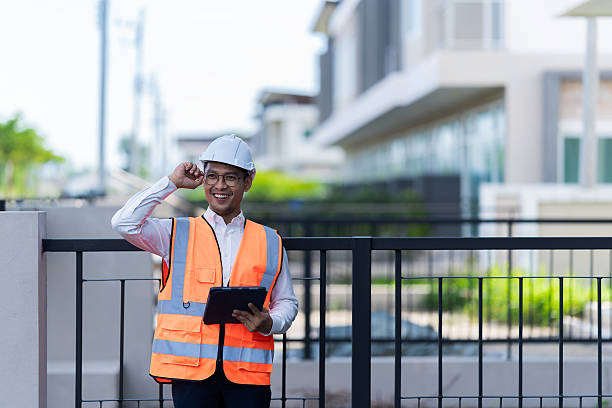 istock Real estate developer inspecting house in project wearing hard hat and using digital tablet. Asian contractor standing in front of new house. Construction industry concept. Real estate. 2234494309
