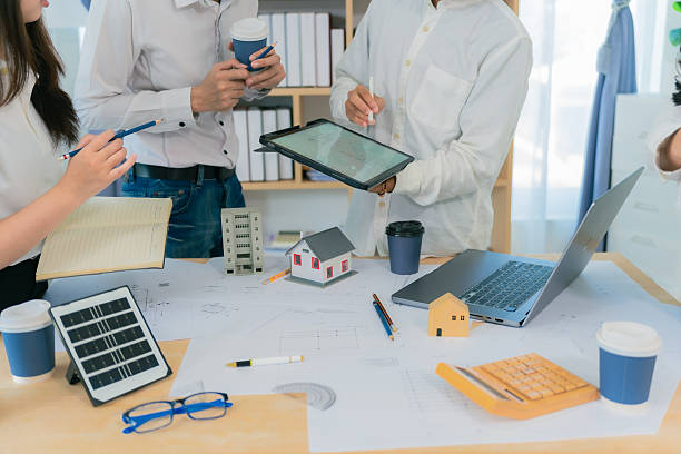 istock Architecture and Construction Concepts - Group of architects with laptop computers meeting with plans on rooftop to plan building design. 2234494343