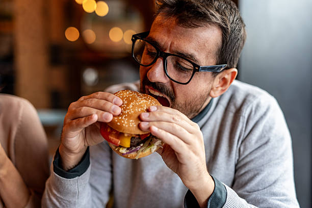 Hungry man eating a delicious burger in a restaurant