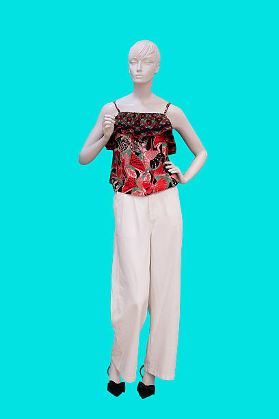 Full length image of a female display mannequin wearing colorful top and white pants isolated on blue background