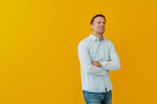 istock Young businessman standing confidently against a bright yellow background while smiling and showcasing a modern and stylish appearance 2234495018