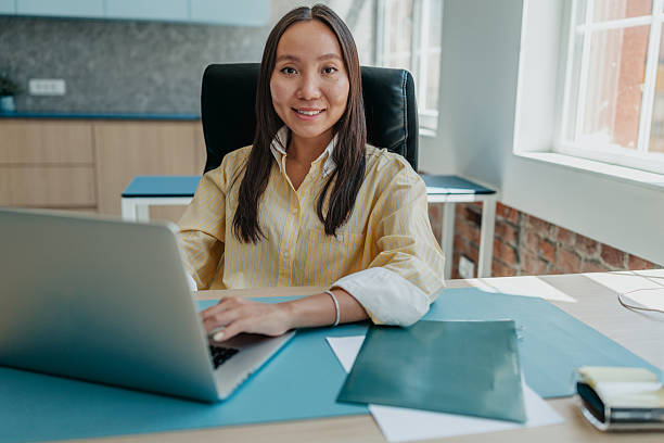 istock Young businesswoman working in a modern office setting with a laptop and documents 2234495072