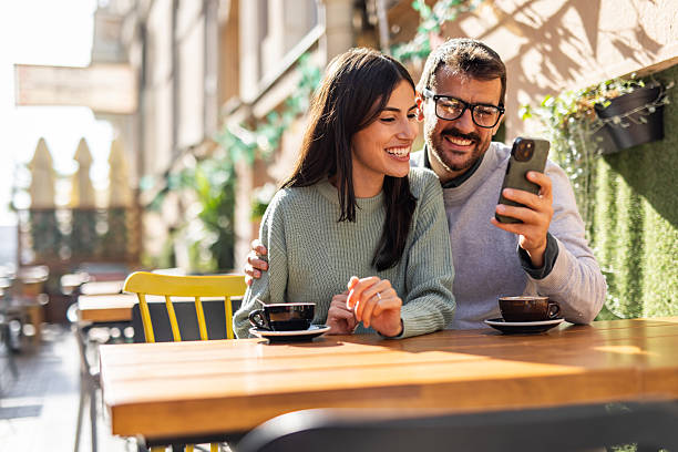 istock Happy couple using smartphone and drinking coffee outdoors 2234495113