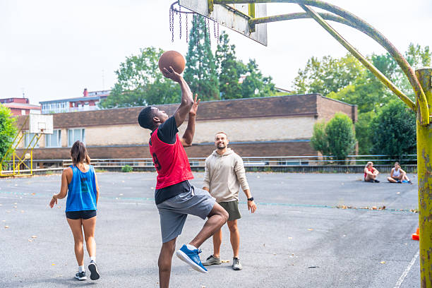 istock Young man shooting a basket while playing basketball with friends 2234495648