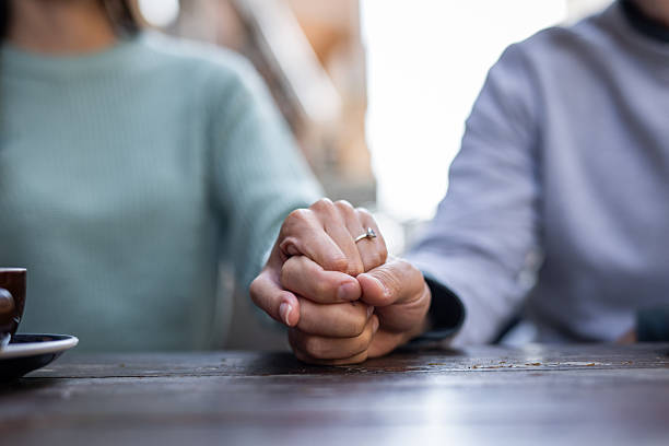 Close-up of a loving couple holding hands at a cafe table, proudly displaying an engagement ring while celebrating their commitment and the joyous beginning of their future together