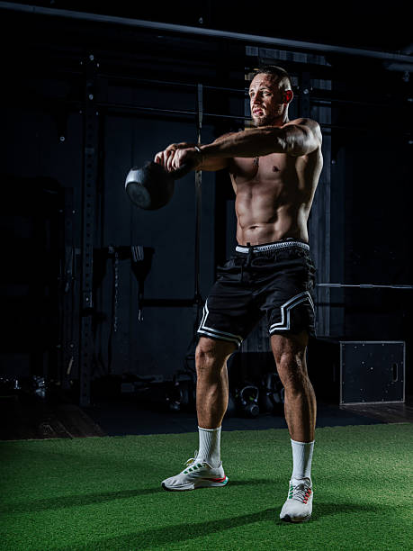 istock Muscular man training with weights. Brutal strong athletic men pumping up muscles workout in dark gym. 2234496535