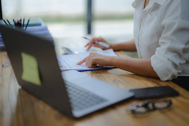 istock Businesswoman in a modern office surrounded by charts and documents, using a calculator to analyze financial data 2234496790