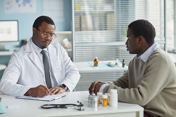 istock Middle Aged Black Male Physician Writing while Listening to Patient Concerns 2234498054
