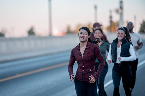 istock Group of Active Individuals Jogging Outside During Dawn on a Scenic Road 2234498493