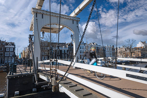 Cyclist crossing the white Magere Brug bridge in Amsterdam, Netherlands, on a sunny day