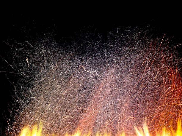 Yellow fire sparks is flying. Beautiful abstract background. Christmas evening at the fireplace. Art trail of firework. Burning trace glowing over black background. Natural pattern with copy space.