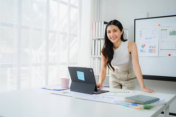istock Confident Asian professional reviewing financial documents, working on digital tablet at sleek workplace workstation 2234505735