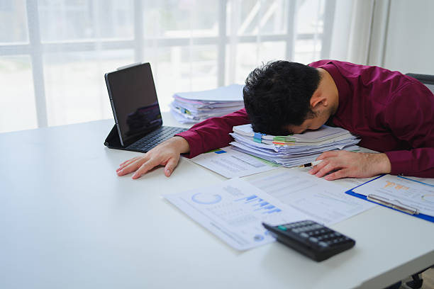 istock Tired professional napping amid scattered paperwork, symbolizing workplace burnout and overwhelming workload pressures 2234505818