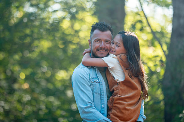 istock Happy Father and Daughter Hugging Outdoors in a Sunlit Forest Scene 2234505979