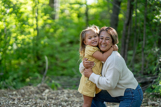 istock Mother and Daughter Embracing in a Sunlit Forest Setting 2234506211
