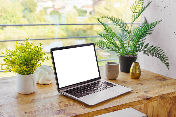 istock Laptop computer with white screen on wooden desk on window background. Mockup, template, copy space 2234507328