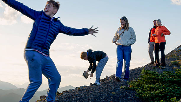 Multi generation family explores mountain ridge crest at sunset over mountains, Canadian Rockies, Alberta