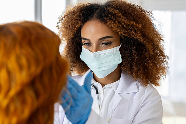 istock Female doctor with mask looking through a patient's tonsils 2234512744