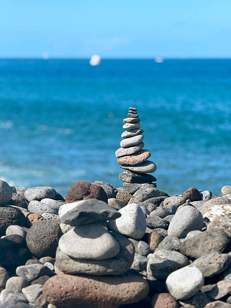 istock Stone Cairns on Rocky Beach with Blue Sea in Background 2234513874