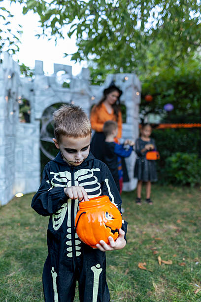 istock Boy in skeleton costume with Halloween pumpkin bucket. 2234514083