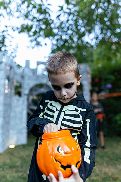 istock Boy in skeleton costume with Halloween pumpkin bucket. 2234514086