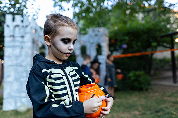 istock Boy in skeleton costume with Halloween pumpkin bucket. 2234514100