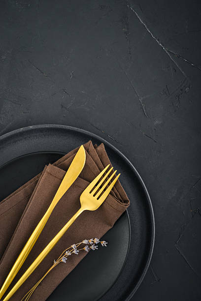 istock table place setting with black plates and golden cutlery on black  background 2234515590