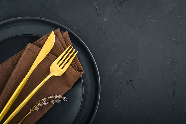 istock table place setting with black plates and golden cutlery on black  background 2234515614