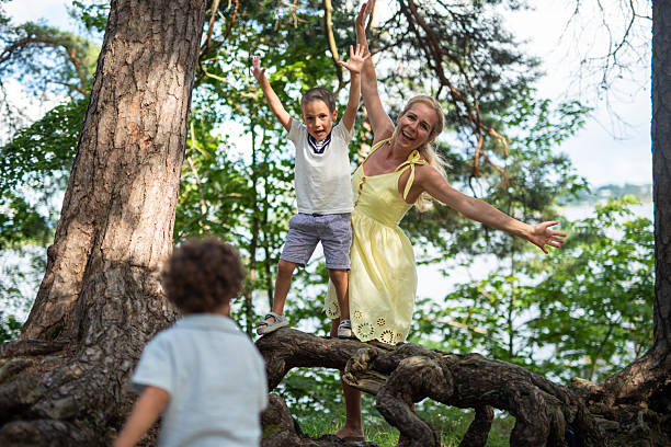 istock Happy family having fun in the forest balancing on a tree root. 2234516519