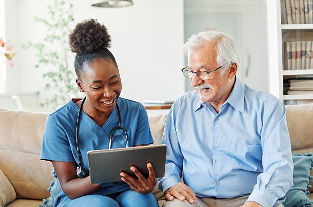 istock nurse doctor senior care tablet computer technology showing caregiver help assistence retirement home nursing elderly woman african american black happy laughing man 2234519282