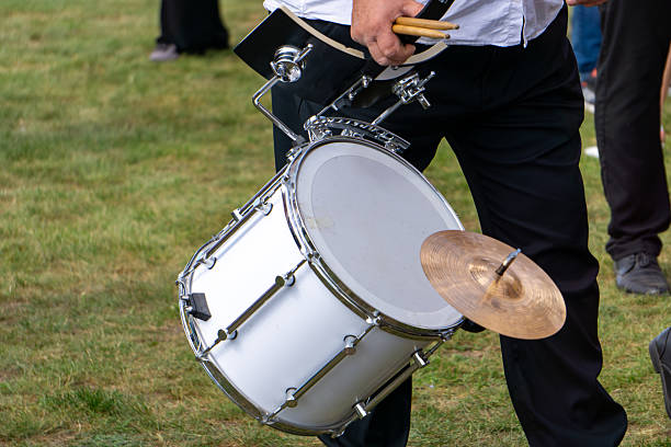 istock Brass band musician playing marching drum with attached cymbal during outdoor performance event. 2234525204