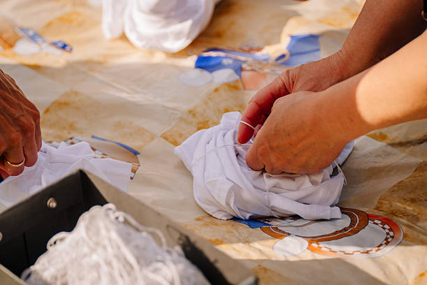 istock Hands tie string around a folded white Tshirt on a table, preparing for tiedye craft outdoors; fabric secured and ready for dye. 2234525631